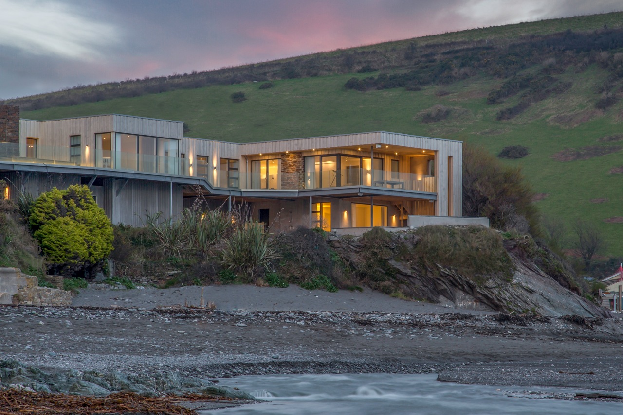 Two storey eco-house on the beach. Frameless glass balustrade around first floor deck.